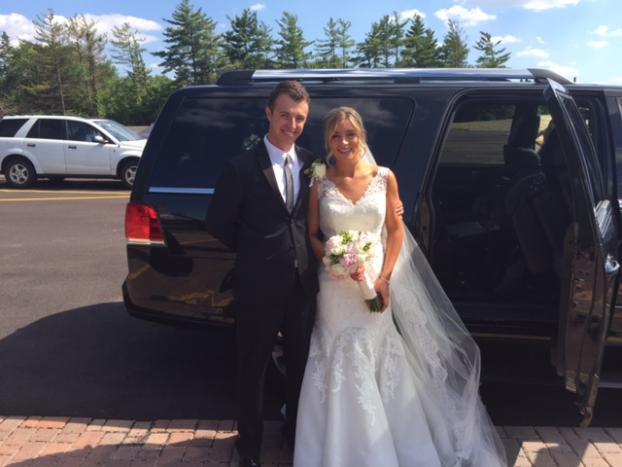 Wedding couple outside a luxury SUV surrounded by trees