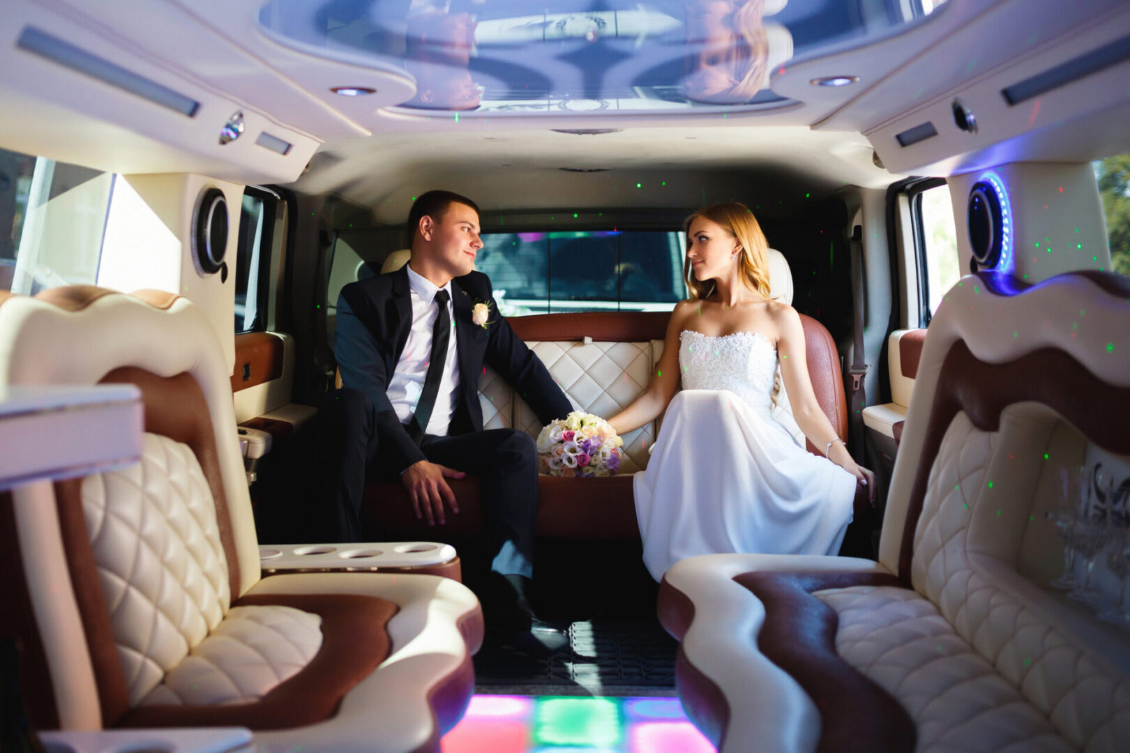 A bride and groom sitting in the back of a limo.