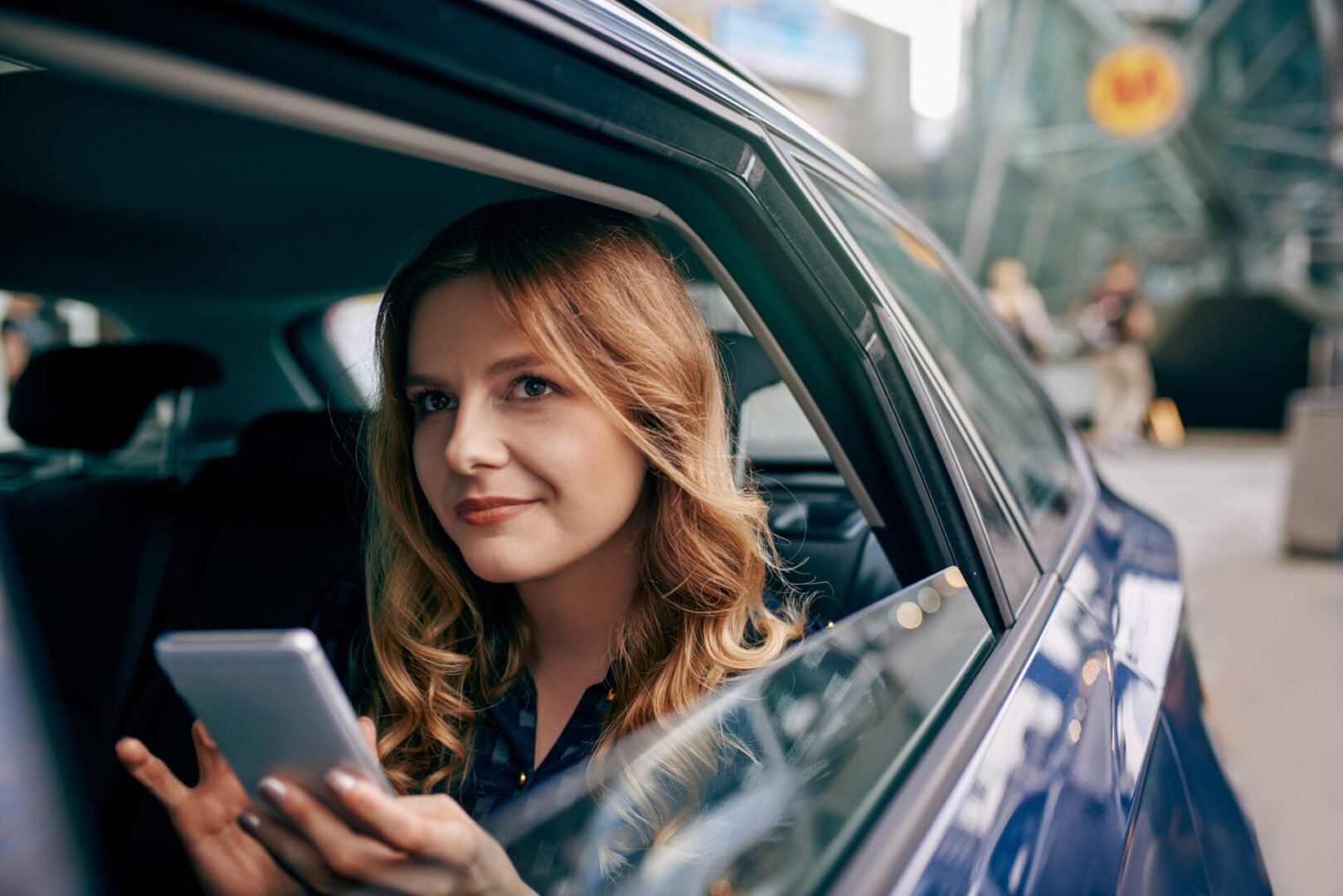 A woman sitting in the passenger seat of a car holding her phone.