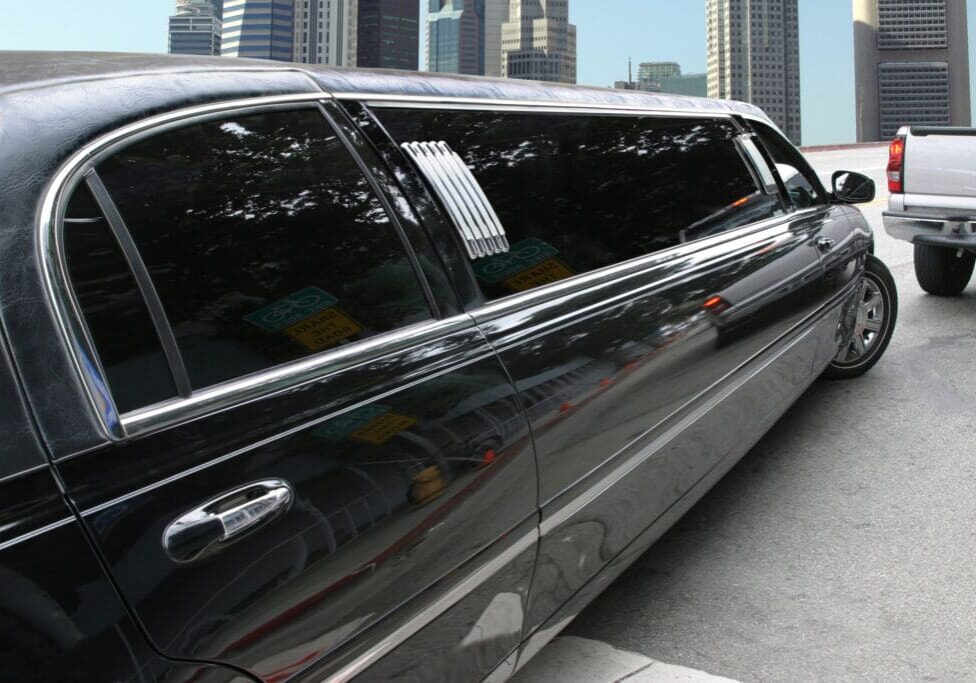 A black limo is parked on the side of the road.